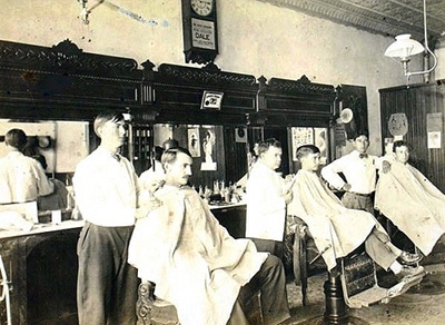 An intriguing old photo captured inside a barbershop, exuding a nostalgic atmosphere with the faint lingering smell of scented hair products and aftershave.