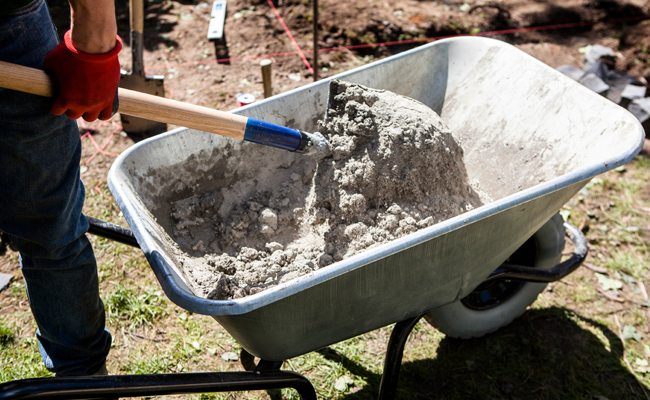 A man pouring concrete into a wheelbarrow in this Beginner's Guide.