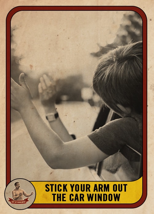 Black white boy holding arm out a car window.