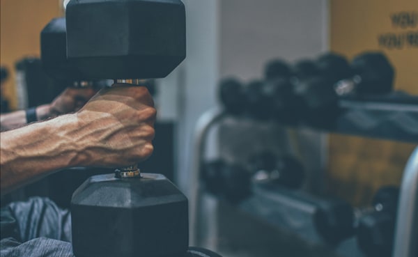 A person showcasing strength by lifting a dumbbell in a gym setting.