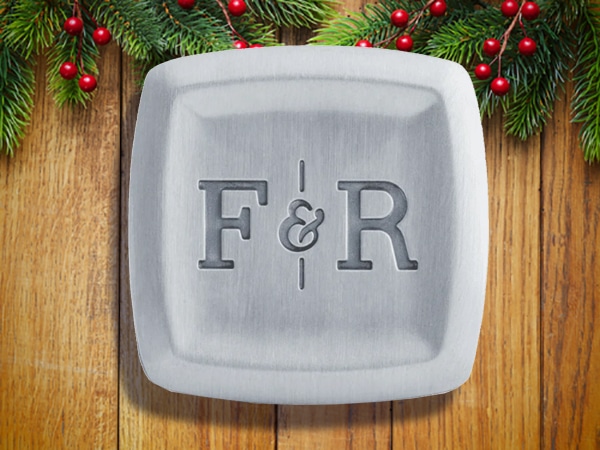Square silver soap bar engraved with “F & R,” placed on a wooden surface with pine branches and red berries—perfect as unique stocking stuffers for men this holiday season.