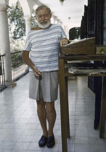 A man with a beard standing next to a table in summer.