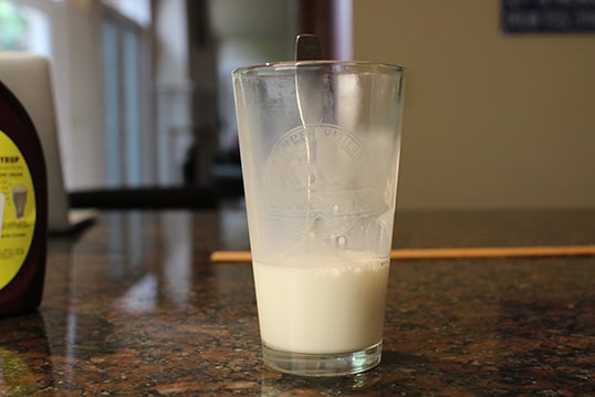 Pour Milk into the glass place a spoon in the glass.