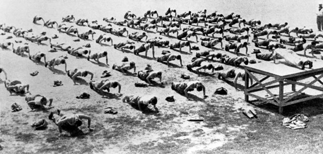 During WWII Workout Week, a large group of people is seen standing in a field.