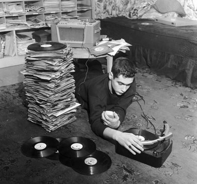 A man, passionate about vinyl record collecting, spins his favorite records as he lays on the floor with a vintage record player.