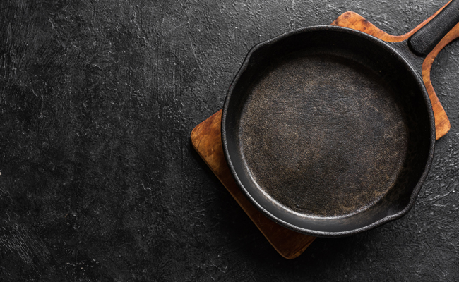A cast iron skillet on a dark background.