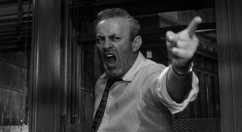 The man is pointing angrily at the door.